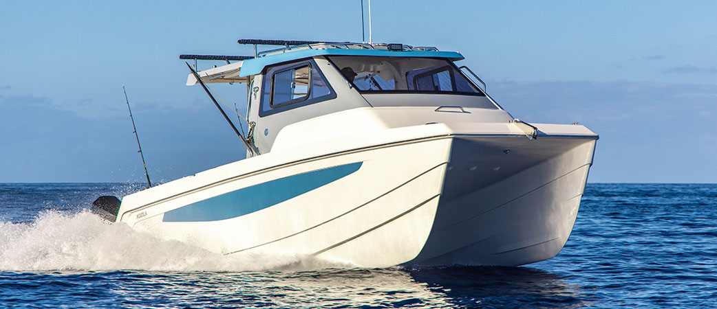 Catamarán a motor Aquila 28 Cuddy navegando a baja velocidad en aguas tranquilas, con una familia disfrutando del sol y la brisa marina.